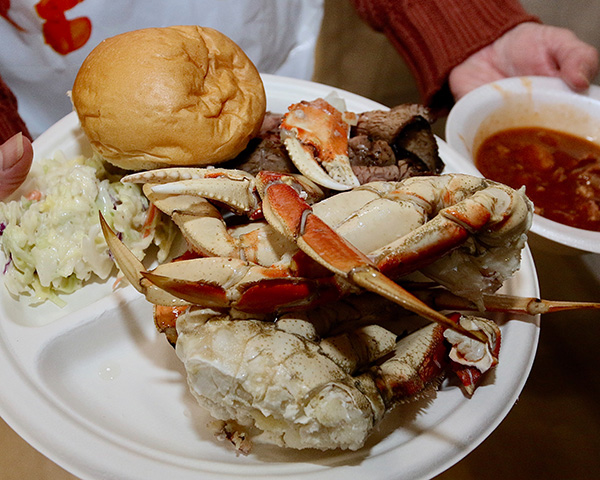 Plate heaping with crab, tritip, coleslaw, roll, and beans
