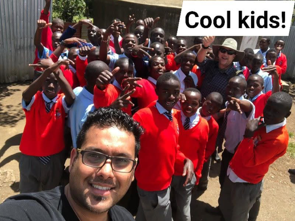 Dr. Rushi Panchal smiling with young Kenyans in the background.