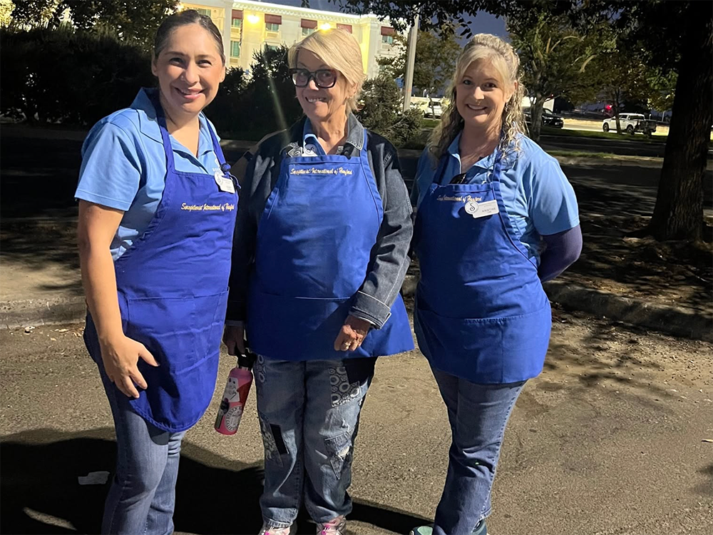 Three Rotarian ladies in blue aprons ready-to-shop.